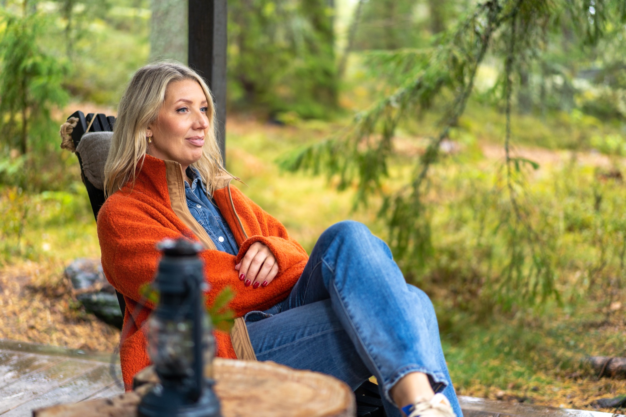 Lina Skandevall i orange jacka på en veranda med utsikt mot skogen